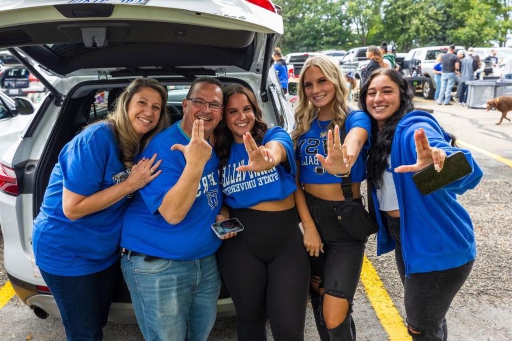 5 people anchoring up outside a car for a tailgate