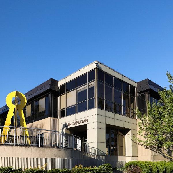 The entrance to a building with the words Mackinac Hall over the entrance. A yellow art sculpture is near the entrance.