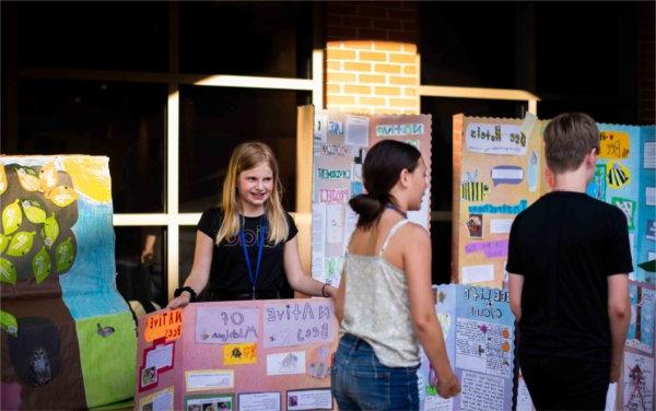 Maria Ochoa, right, stands near Grand Rapids Montessori student projects during the Groundswell Stewardship Initiative student project showcase on the Pew Grand Rapids Campus May 15.