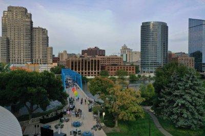 A group of people gather on a blue bridge with a city skyline in the background.