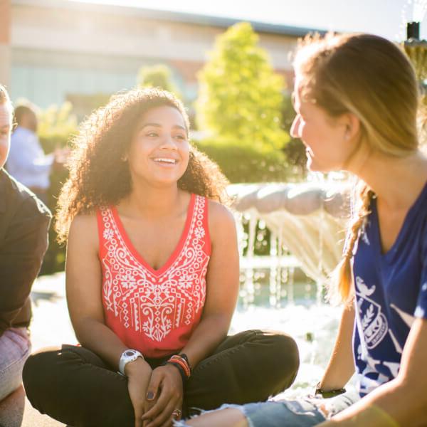 A photo of students talking by a fountain on campus. 