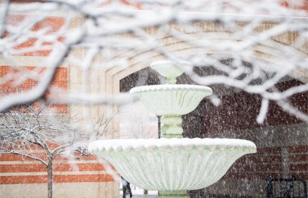  大学校园里的雪景里有一座喷泉. 