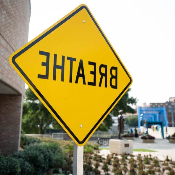 A yellow sign with the word "breathe" is shown outside a building.