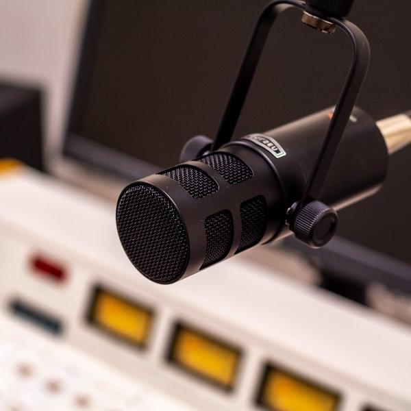 A studio microphone for a radio station hangs over the control board.