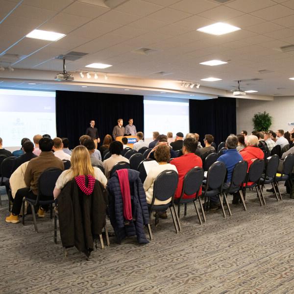 A group of students presents on their senior project in front of a room full of people.